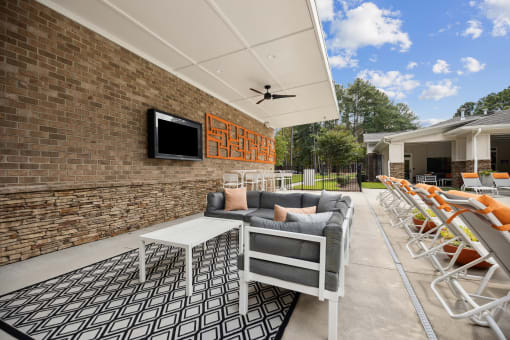 a patio with couches and chairs and a table and a television