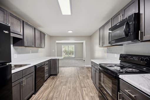 a kitchen with black appliances and white counter tops and wooden floors