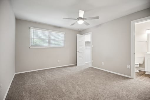 an empty room with carpet and a ceiling fan