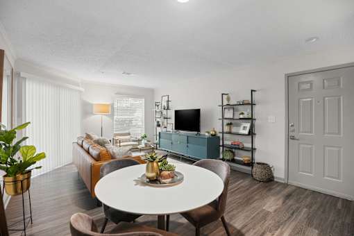 A living room with a white table and brown chairs.