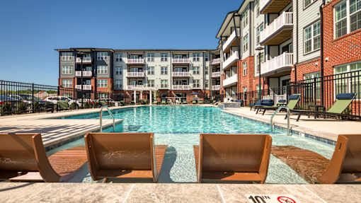 A pool surrounded by chairs and buildings.