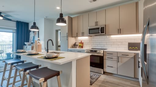 a kitchen with a large island and stools in front of a counter top at Aura Stonebridge, Richmond