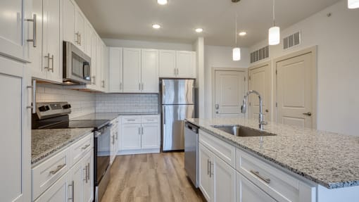 a kitchen with marble counter tops and white cabinets at The Walker Virginia Center, Glen Allen, VA