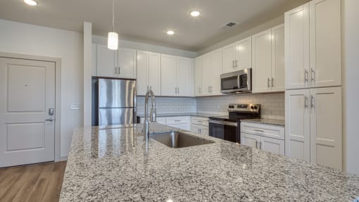an open kitchen with granite counter tops and white cabinets at The Walker Virginia Center, Glen Allen, Virginia