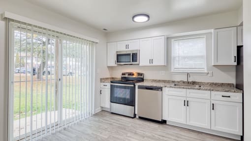 a kitchen with white cabinets and a sliding glass door