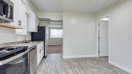 an empty kitchen with white cabinets and stainless steel appliances