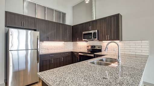 A kitchen with a granite countertop and stainless steel appliances.