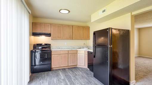 A black refrigerator is in a kitchen with wooden cabinets.