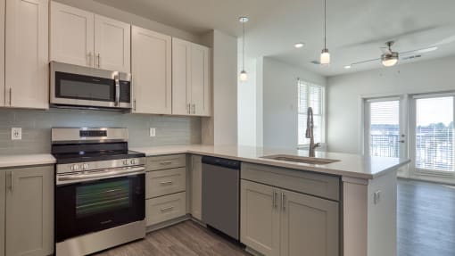 an empty kitchen with white cabinets and stainless steel appliances at The Port at East Beach Apartments and Marina, Norkfolk, VA
