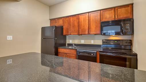 A kitchen with wooden cabinets and black appliances.