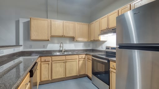 an empty kitchen with stainless steel appliances and wood cabinets