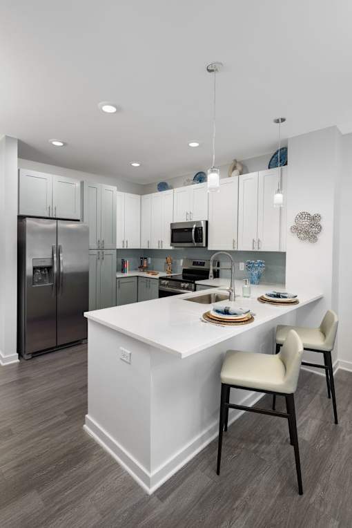 A modern kitchen with a white island and two chairs.