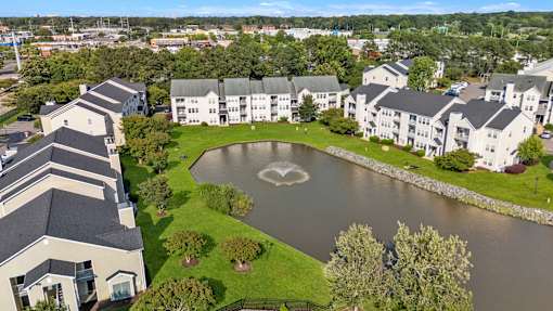 A large white building with a black roof is surrounded by a pond with a heart-shaped design in the middle.