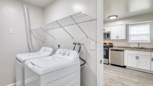 a white utility room with a washer and dryer and a kitchen