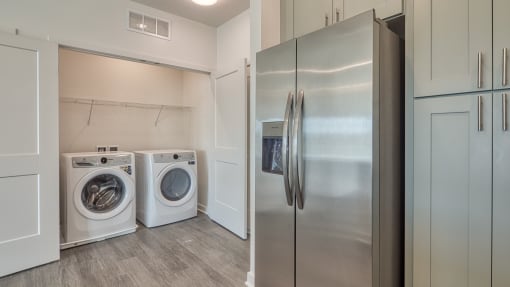 a laundry room with a washer and dryer and a stainless steel refrigerator at The Port at East Beach Apartments and Marina, Norkfolk, VA
