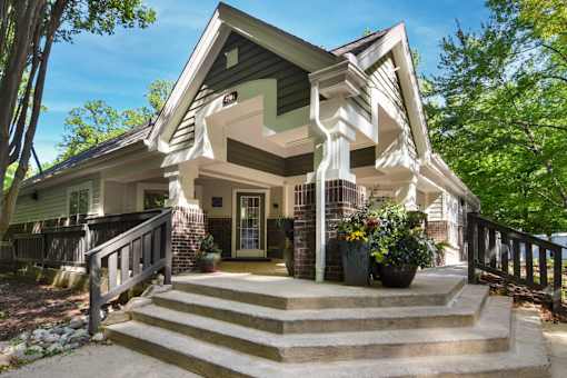 A house with a green roof and a porch with steps leading up to it.