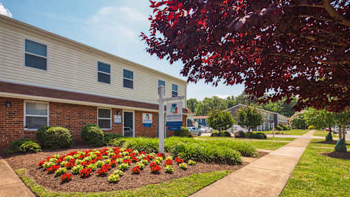 A building with a sign in front of it and a flower bed in the front.