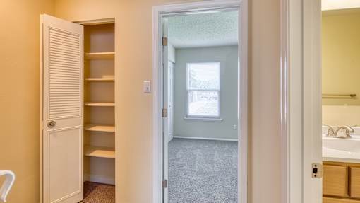 A white door is open to a room with a window and a sink.
