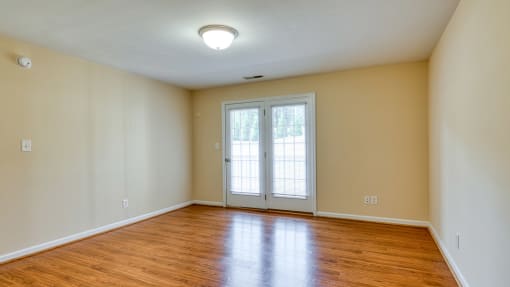 the living room of an empty house with wood floors and a door to a balcony