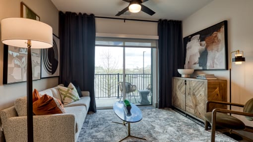 a living room with a couch and a door to a balcony at Aura Stonebridge, Richmond, 23225