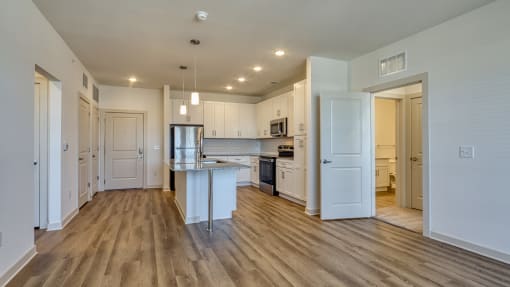 an open kitchen and living room with white walls and wood flooring at The Walker Virginia Center, Glen Allen, VA, 23059