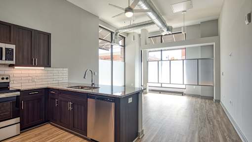 A modern kitchen with dark wood cabinets and stainless steel appliances.