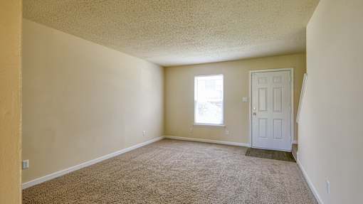 A room with a carpeted floor and a white door.