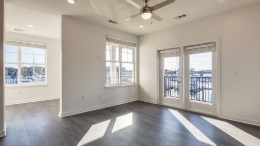 an empty living room with windows and a ceiling fan at The Port at East Beach Apartments and Marina, Norkfolk, VA, 23518