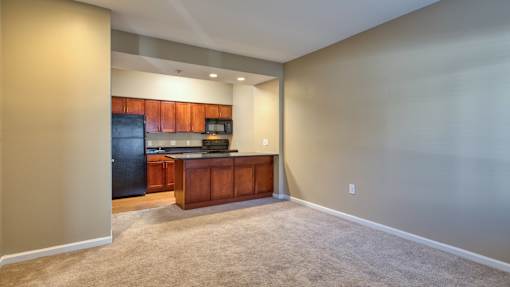 A kitchen with a black refrigerator and wooden cabinets.