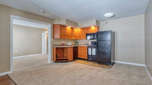 A kitchen with brown cabinets and a black fridge.