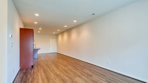 a living room with white walls and wood flooring and a sink