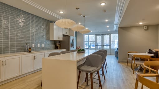 an open kitchen and dining area with a long counter and chairs at The Bella at Westchester, Virginia