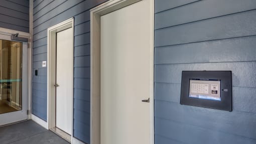 a white door to a blue building with an automated door sensor on the side