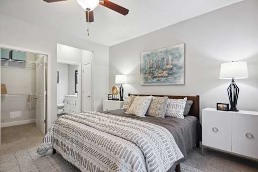 A bedroom with a bed, nightstand, and a painting on the wall.