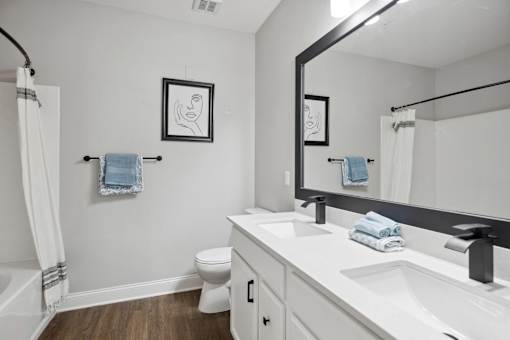 A bathroom with a toilet, sink, and mirror.