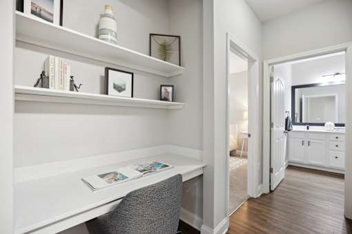A white desk with a grey chair and a book on it.