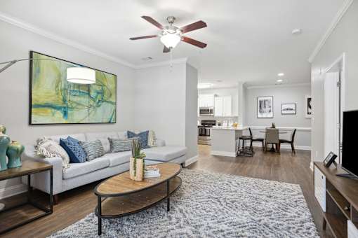 A living room with a grey couch and a painting on the wall.