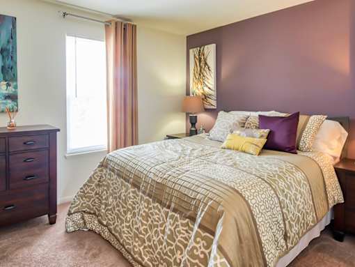 A bedroom with a large bed and a dresser.
