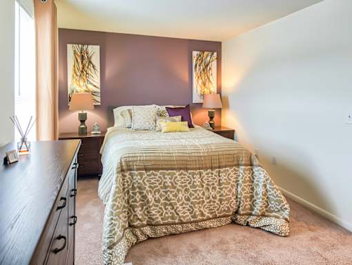 A bedroom with a bed, nightstand, and lamp.