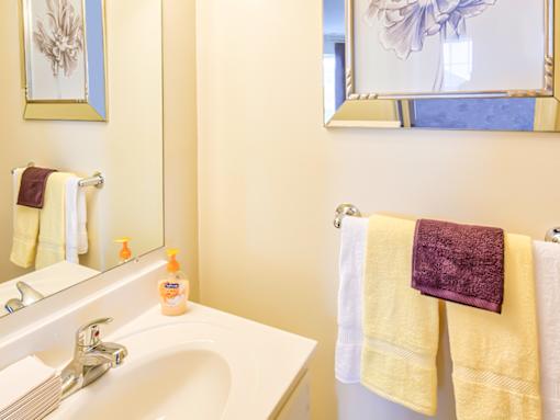 A white sink with a purple towel hanging on the towel rack.