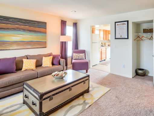 A living room with a brown couch and a painting on the wall.