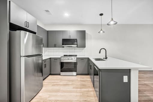 A modern kitchen with stainless steel appliances and wooden flooring.