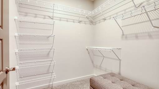 A room with a pink ottoman and a wall-mounted shelving unit.