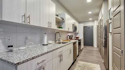 A kitchen with a granite counter top and stainless steel appliances.