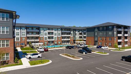 A parking lot in front of a multi-story apartment building.