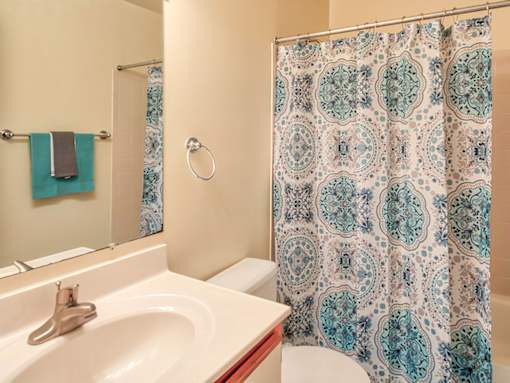 A bathroom with a white sink and a shower curtain with a blue and white pattern.