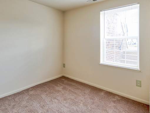 A room with a window and carpeted floor.