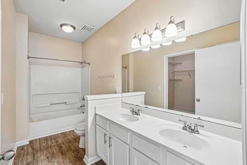 A bathroom with a white vanity and a large mirror.