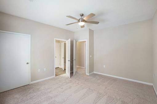 A room with a ceiling fan and carpeted floor.