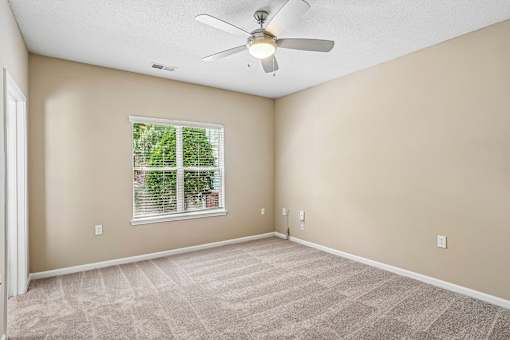 A room with a ceiling fan and a window with blinds.